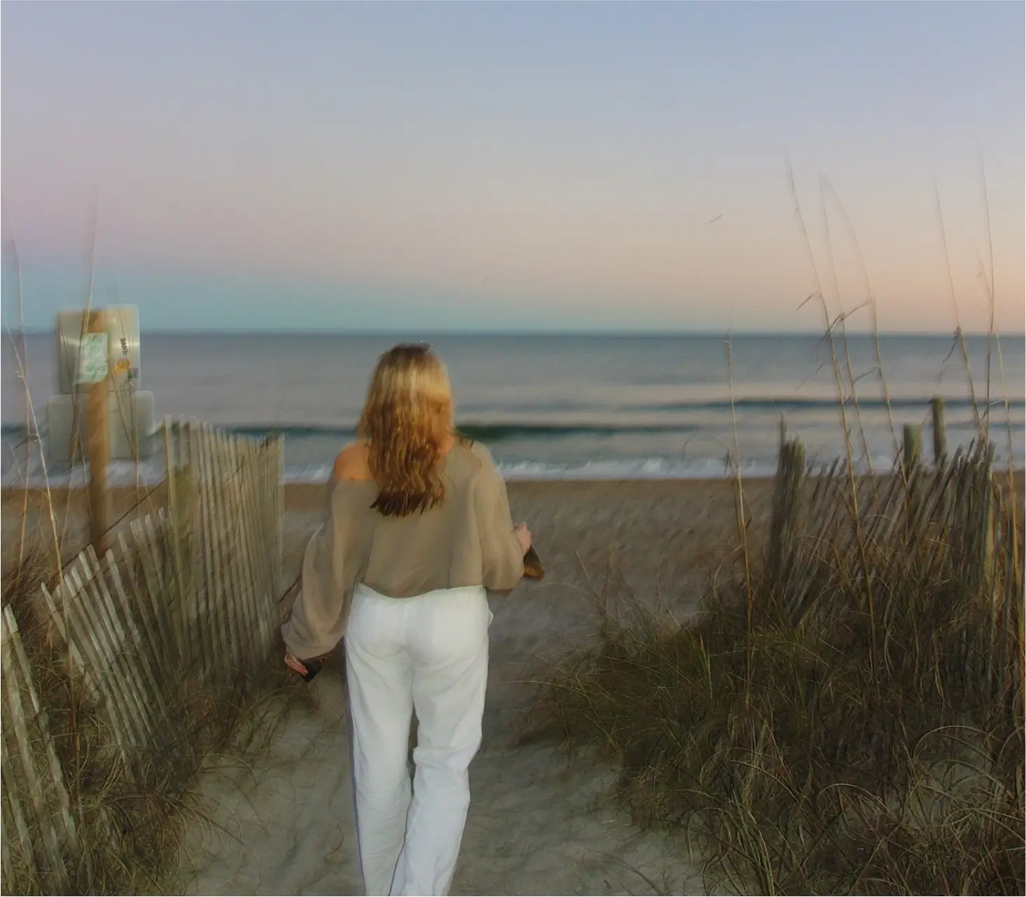 Woman walking on a peaceful North Carolina beach path at sunset